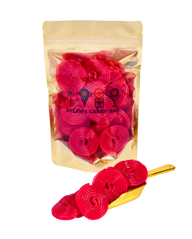 Strawberry Licorice Wheels in resealable gold mylar bag next to Strawberry Licorice Wheels overflowing from gold scoop