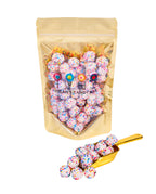 Vanilla Crème Covered Pretzel Balls in resealable gold mylar bag next to Vanilla Crème Covered Pretzel Balls overflowing from gold scoop